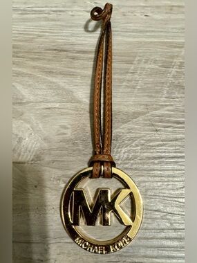 Michael Kors Logo Keychain: Gold and Brown. A gold Michael Kors logo pendant,